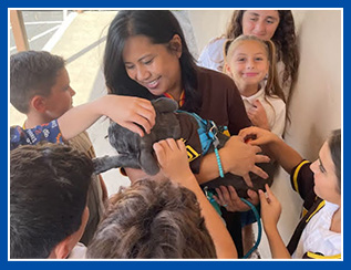 students around teacher and petting dog in her arms